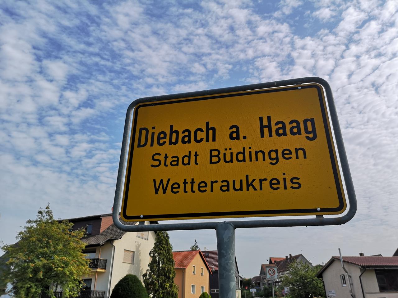 Ortsschild von Diebach am Haag mit H�usern und Wolken im Hintergrund